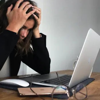 Femme stressée devant un ordinateur portable, se tenant la tête