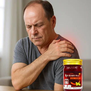 Un homme masse son épaule douloureuse avec un baume rouge thaïlandais pour soulager efficacement.