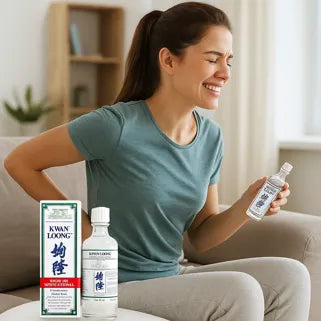 Une femme masse son bas du dos avec l’huile Kwan Loong pour soulager la douleur.