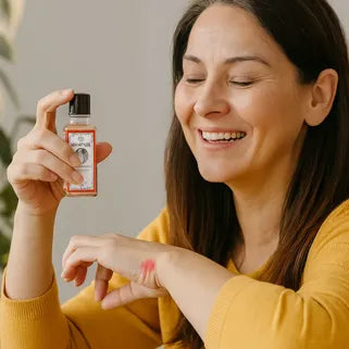 Femme souriante appliquant l’huile Siang Pure à la menthe sur la peau de sa main.