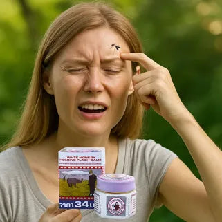 Une femme applique un baume sur son front après une piqûre d’insecte, expression douloureuse.