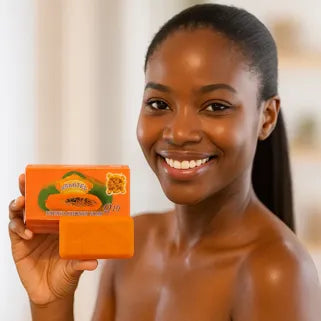 Femme souriante tenant un savon papaye pour une peau éclatante, douce et lumineuse.