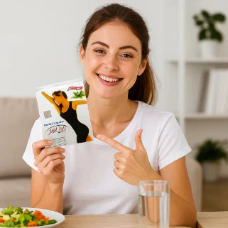 Femme souriante à table pointant un sachet de produit minceur à côté d'une salade.