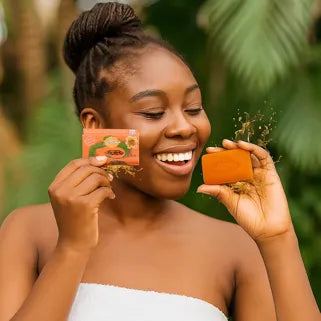 Femme souriante tenant un savon éclaircissant à la papaye pour soin anti-taches pigmentaires naturel.