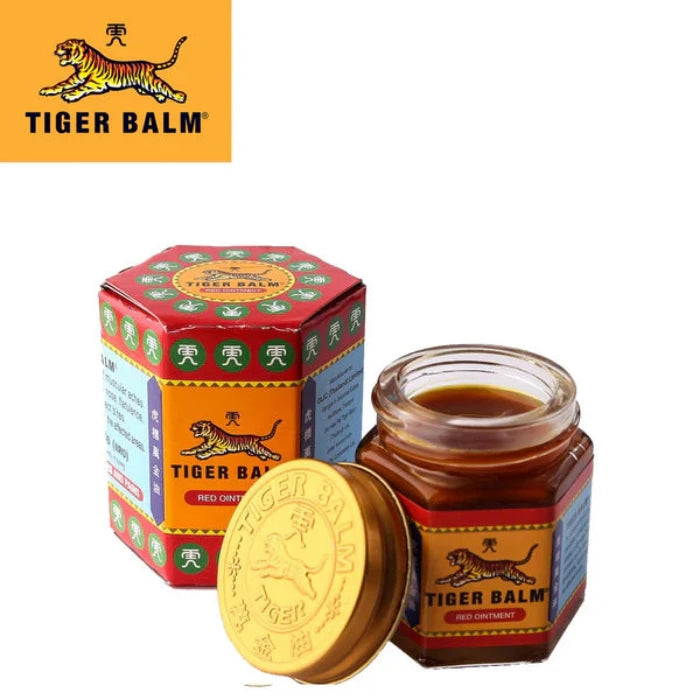 Petit pot de "Tiger Balm" "Baume du Tigre" (pommade rouge) avec couvercle doré, à côté de son emballage rouge et vert. Étiquette avec tigre et texte "TIGER BALM RED OINTMENT".