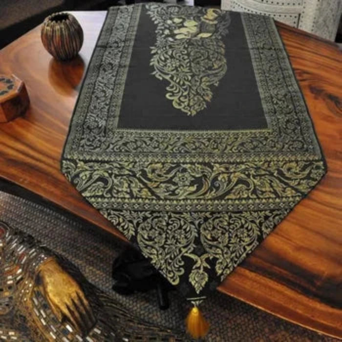 Chemin de Table en Tissu Noir avec Pompons Dorés. Nappe présentée sur une table en bois