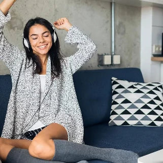 Jeune femme souriante écoutant de la musique sur un canapé bleu