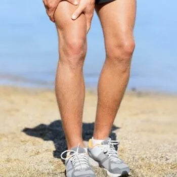 Coureur souffrant de la douleur à la jambe sur la plage