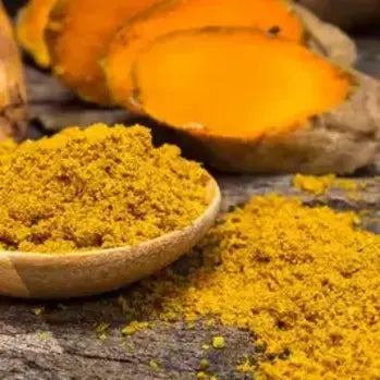 Poudre de curcuma jaune dans une cuillère en bois