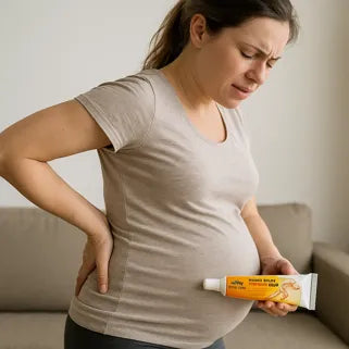 Femme enceinte souffrant du dos tenant un tube de baume du tigre contre son ventre.
