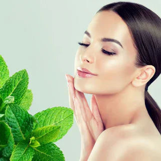 Femme détendue aux yeux fermés, respirant la fraîcheur de feuilles de menthe verte éclatante.