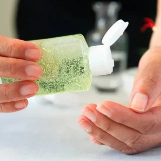 Une personne applique du désinfectant pour les mains en gel vert.