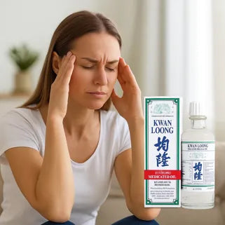 Une femme masse ses tempes avec l’huile Kwan Loong pour apaiser les maux de tête.