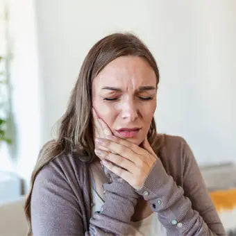 femme avec mal de dents qui se tient le visage