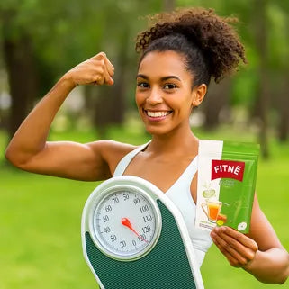 Femme souriante tenant une balance, un sachet de thé minceur, dans un parc verdoyant. 