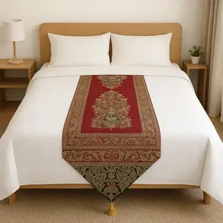 Lit double avec draps blancs et chemin de lit rouge orné de motifs floraux dorés.