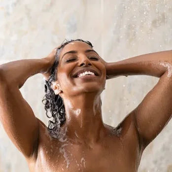 Femme souriante se lavant les cheveux sous la douche