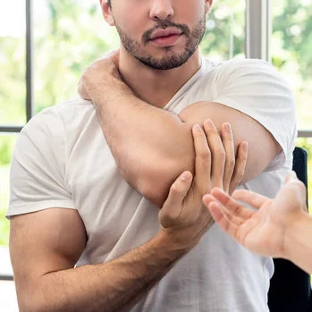 Homme en t-shirt blanc se touchant le coude, expression de douleur