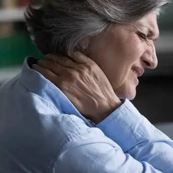 Une femme âgée tenant son cou avec une expression de douleur