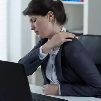 Femme d'affaires massant son cou douloureux devant un ordinateur portable au bureau