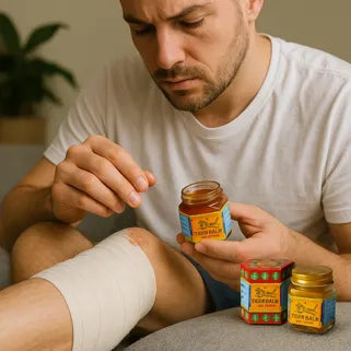Hombre aplicando bálsamo del tigre rojo en su rodilla vendada, después de una lesión.