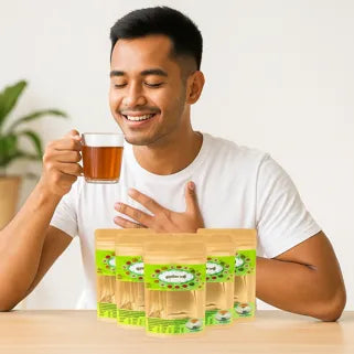 Homme souriant dégustant une infusion bien-être thaïlandaise naturelle avec sachets Tapee posés sur table.