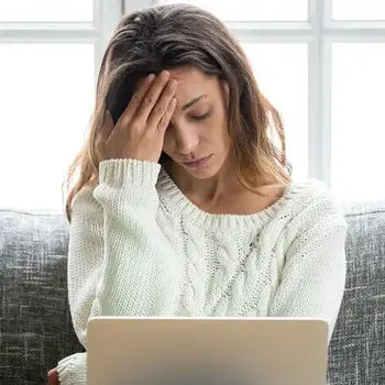 Femme stressée devant un ordinateur tenant sa tête avec fatigue