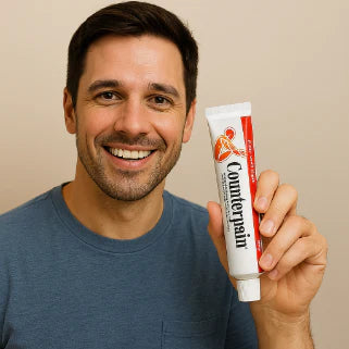 Homme souriant tenant un tube de gel Counterpain, soulagé après application sur son bras douloureux.