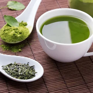 Tasse de thé vert fitné avec feuilles et poudre de thé.