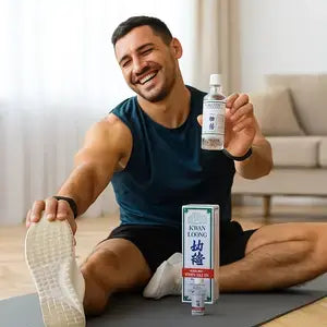 Homme souriant s'étirant sur un tapis de sport, présentant l'huile Kwan Loong pour la récupération.