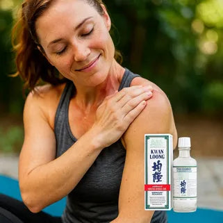 Une femme applique l’huile Kwan Loong sur son épaule pour apaiser douleur et tension musculaire naturelle. 