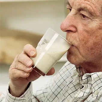 un homme age boit du lait de riz