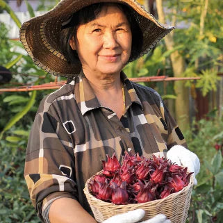 Une jardinière souriante portant un chapeau, tenant un panier de fruits rouges.