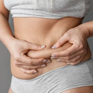 Des mains pincent doucement la peau du ventre pour mesurer la graisse.