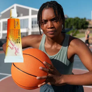 Femme afro-américaine avec un tube de crème musculaire e tenant un ballon de basket.