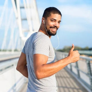 Un homme se tient sur un pont, faisant un pouce levé, promouvant les bienfaits des capsules de Stevia pour la santé