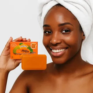 Donna sorridente con asciugamano, che tiene un sapone schiarente alla papaya per pelle nera.
