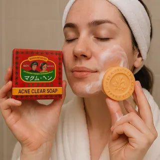 Femme appliquant un savon anti-acné thaïlandais, montrant l’emballage rouge et le produit mousseux. 
