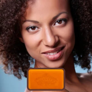 Femme afro-américaine aux cheveux bouclés locataire un savon orange.