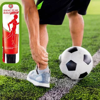 Footballeur applique crème massage sur jambe près ballon sur gazon