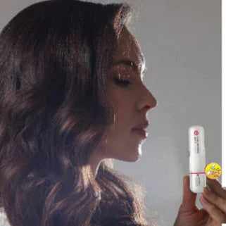 Femme aux cheveux ondulés tenant un inhalateur nasal Siang Pure, en pleine inspiration apaisante.