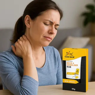 Une femme souffrant de douleurs au cou tient un baume Tiger Balm pour le cou et les épaules.