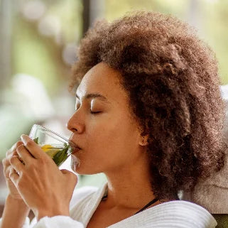 Femme aux cheveux afro savourant une tasse de thé