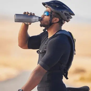 Cycliste en tenue sportive buvant de l'eau pendant une randonnée