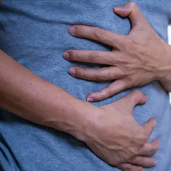 Deux mains posées sur un tissu bleu montrant un signe de douleur abdominale ou thoracique