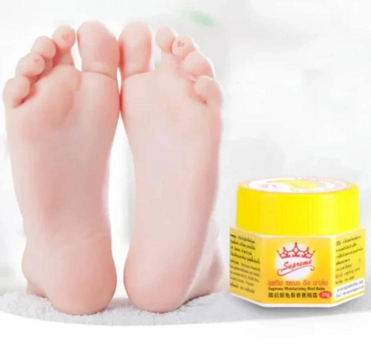 Pieds lisses et soignés reposant sur une surface blanche, accompagnés d’un baume hydratant Supreme pour talons. L’image met en avant un soin réparateur destiné à adoucir, nourrir et protéger la peau sèche ou abîmée des pieds, illustrant un résultat doux et sain.