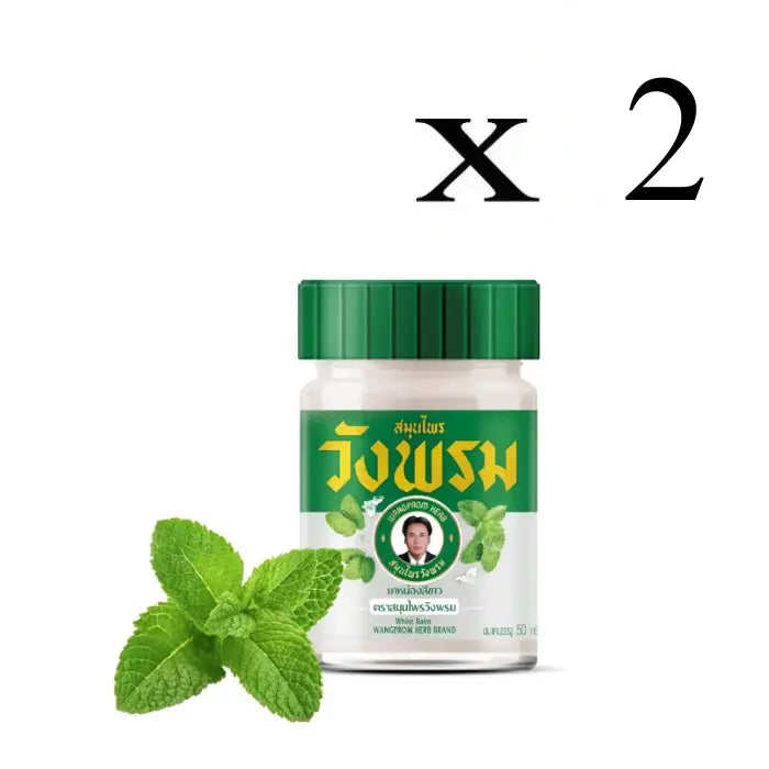 Deux Pots de baume blanc Wangprom Herb avec couvercle vert, étiquette verte en thaï et anglais avec des feuilles de menthe, et feuilles de menthe en premier plant