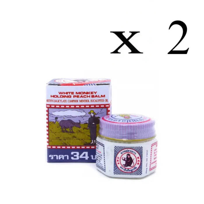 Produit appelé 'White Monkey Holding Peach Balm' avec un pot en verre et son emballage en carton. L'étiquette indique les ingrédients : Methylsalicylate, Camphre, Menthol, Huile d'Eucalyptus. Une illustration sur la boîte montre une personne avec un buffle dans un champ.Lot de 2