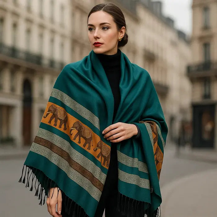 Femme élégante portant un foulard en soie bleu canard orné de motifs éléphants dorés et bruns.