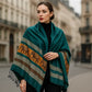Femme élégante portant un foulard en soie bleu canard orné de motifs éléphants dorés et bruns.